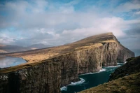 Cliffes majestosos das Terras Altas com vista para águas turquesas e um horizonte nublado