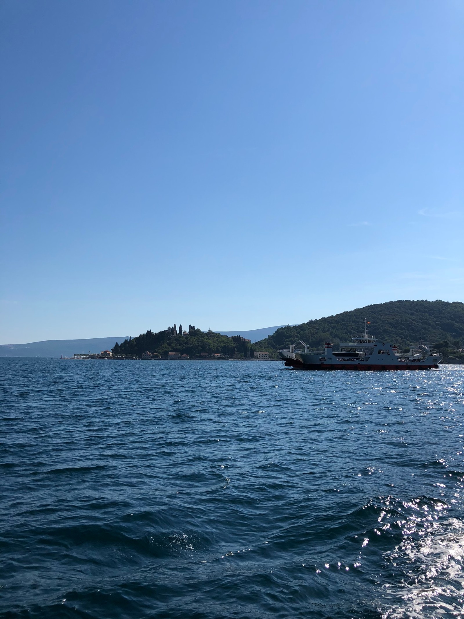 Il y a un bateau dans l'eau près d'une colline (mer, ressources en eau, liquide, promontoire, océan)