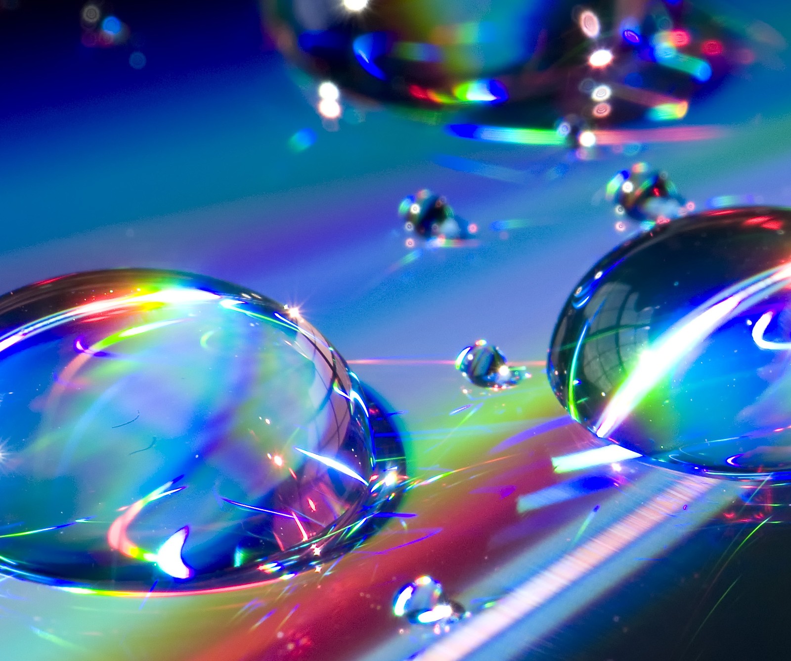 A close up of a bunch of water droplets on a surface (colorful, prism, rainbow, water, water droplets)