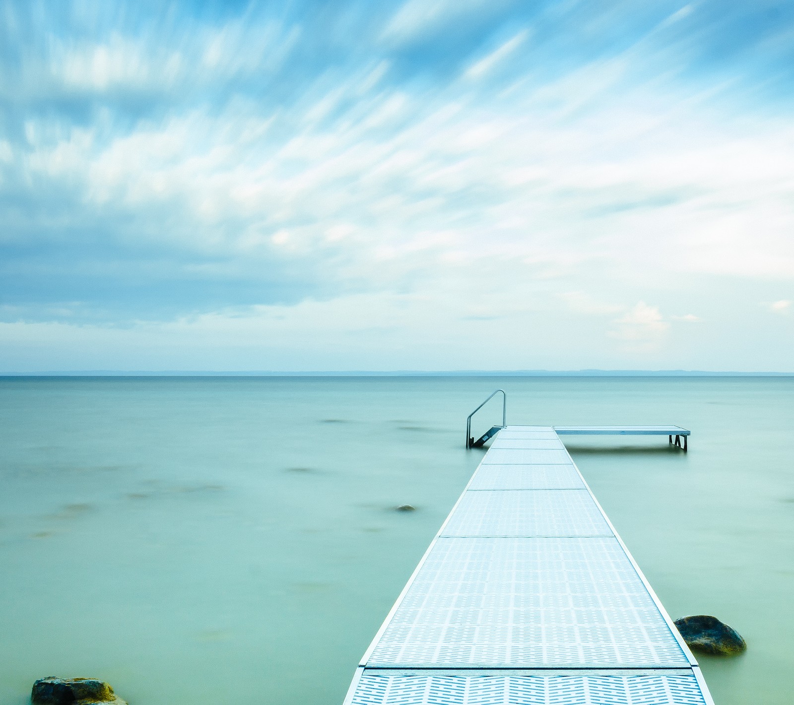 Il y a une longue jetée au milieu de l'eau (matin, peacefull, mer)