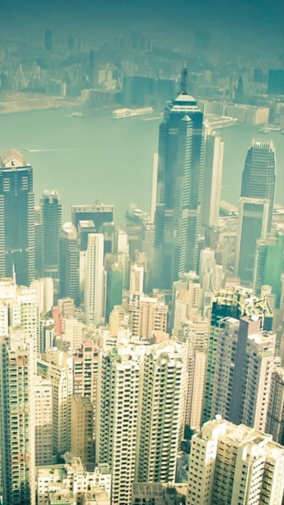 Aerial view of towering skyscrapers against a hazy sky and waterfront.