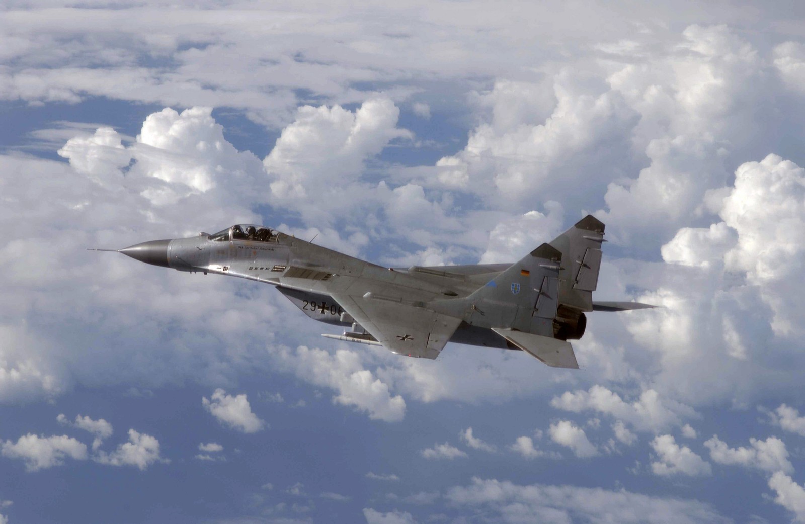 There is a fighter jet flying through the clouds in the sky (mig 29, aircraft, airplane, military aircraft, air force)