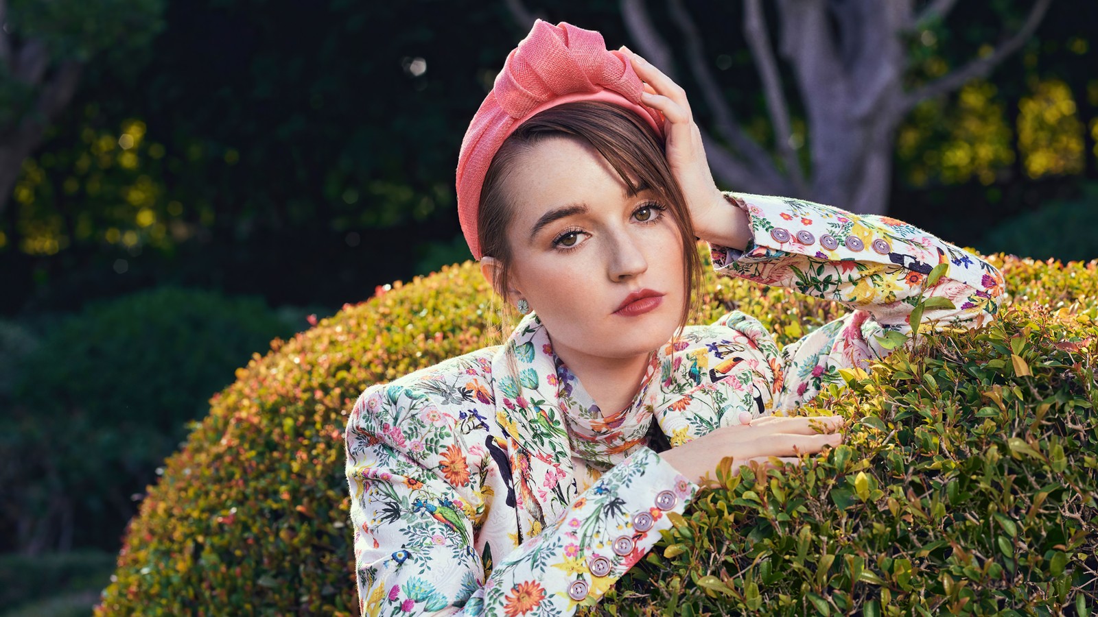 Femme arabe en chemise fleurie et turban rose s'appuyant sur une haie (kaitlyn dever, américain, actrice, célébrité, filles)