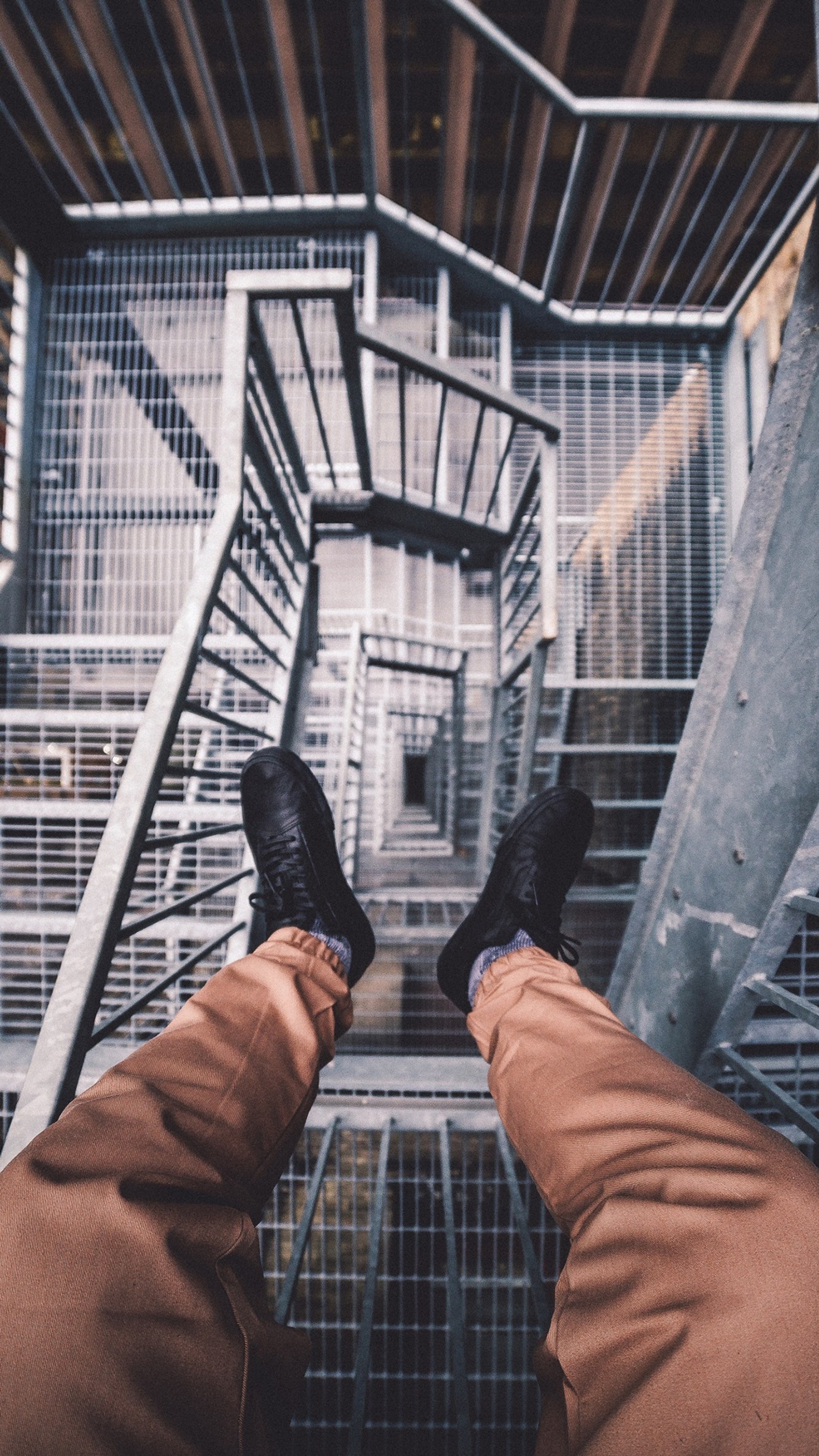 Someone is standing on a metal staircase with their feet up (architecture, mathematics, hand, shoe, gesture)