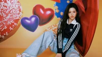 Sullyoon from Nmixx poses stylishly against a vibrant backdrop of hearts and sweets, showcasing a youthful and playful vibe.