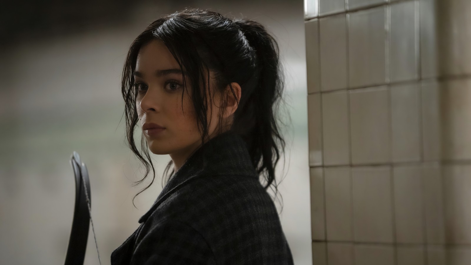 Eine frau mit einem messer im badezimmer neben einer wand (hailee steinfeld, hawkeye serie, hawkeye, kate bishop)