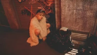 Yeonjun from TXT in a stylish fur coat, squatting next to trash bags in a gritty urban setting, exuding a rebellious vibe.