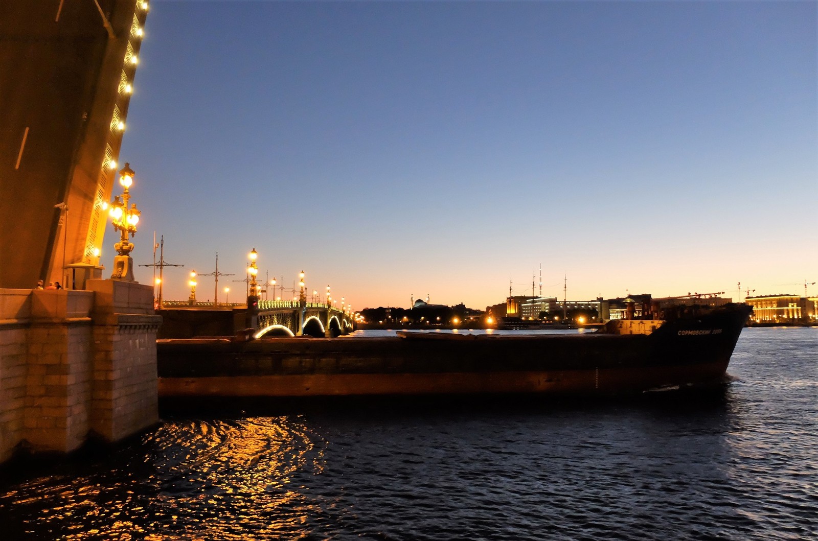 Vista panorâmica de uma ponte sobre um corpo d'água à noite (reflexo, transporte aquático, noite, via navegável, barco)