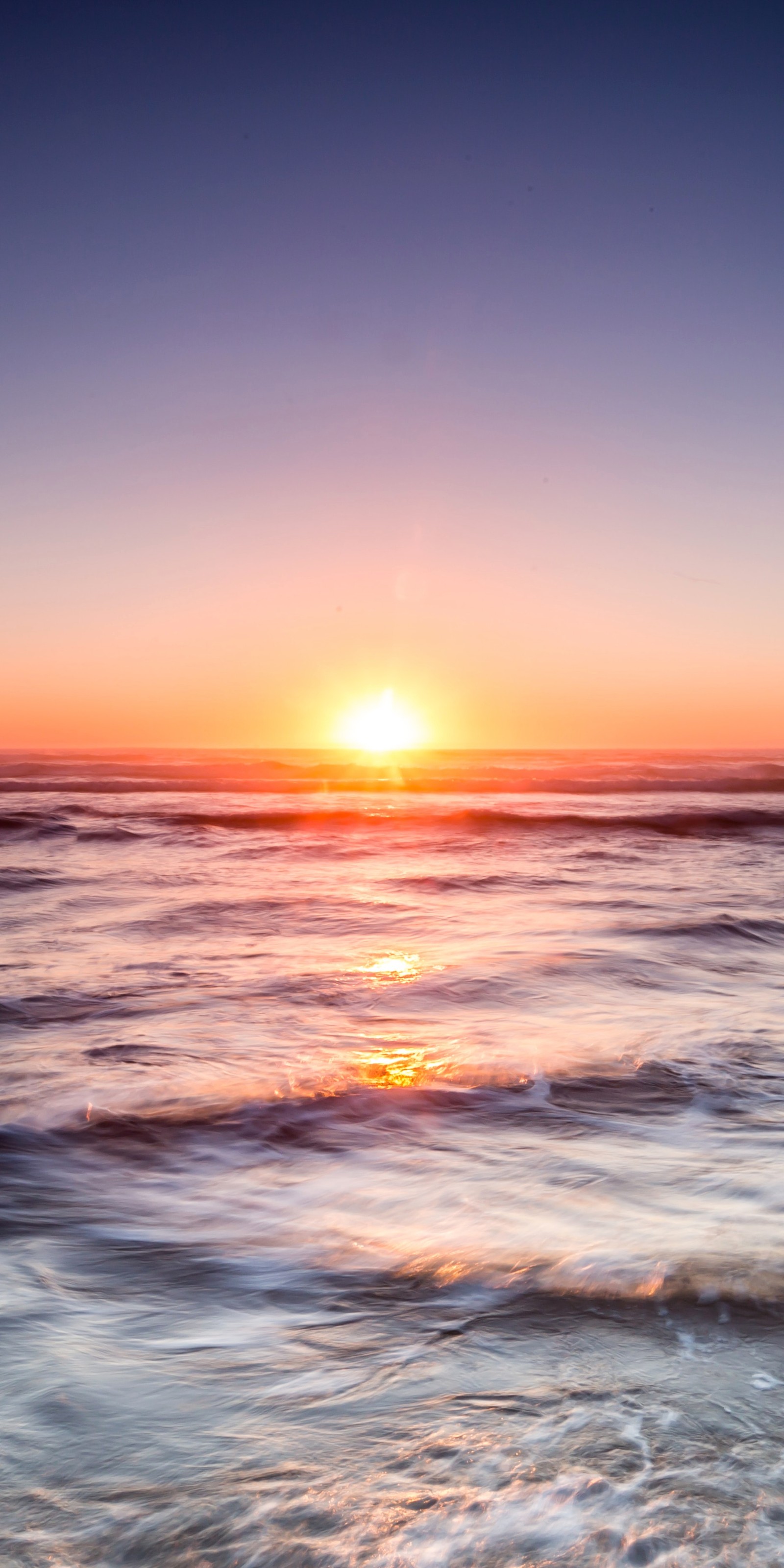 Coucher de soleil sur l'océan avec des vagues et un surfeur au premier plan. (océan, nature, eau, crépuscule, liquide)