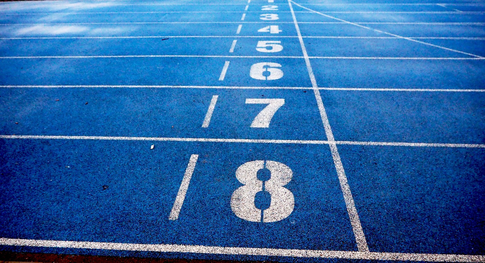 A close up of a blue track with numbers on it (track and field, running, athlete, competition, blue)