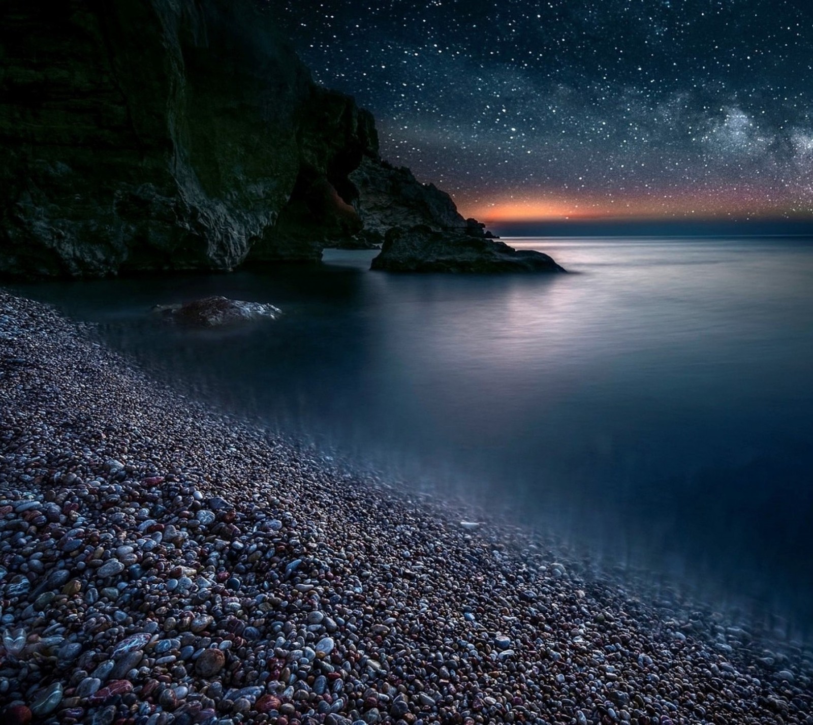 Céu noturno sobre o oceano com uma costa rochosa e uma praia. (paisagem, natureza, mar, céu, estrelas)