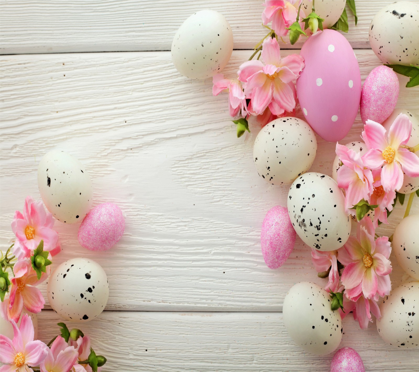 Un primer plano de un montón de huevos con flores sobre una mesa (pascua, feliz)