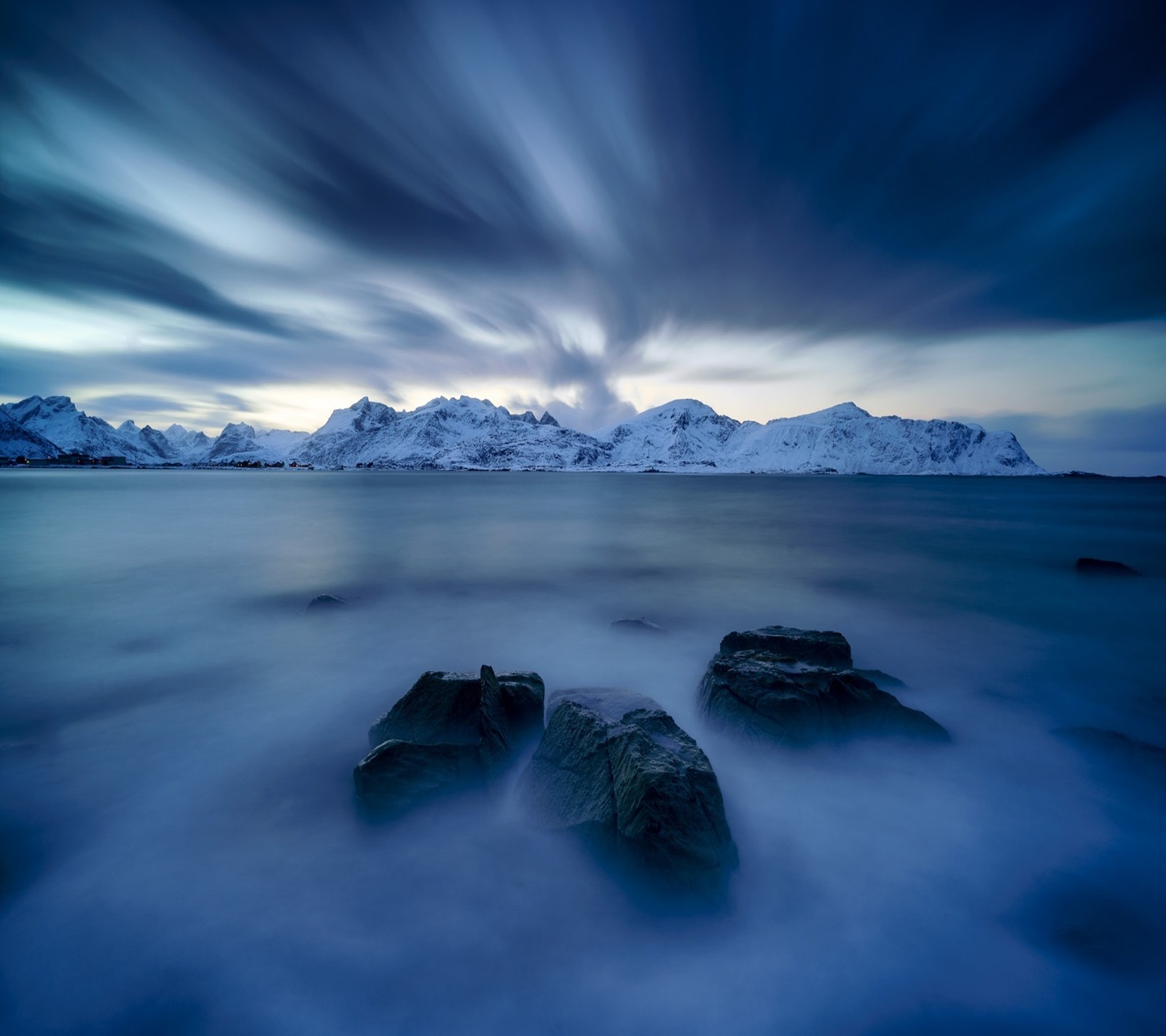 A view of a mountain range with a body of water and rocks (landscape, nature)