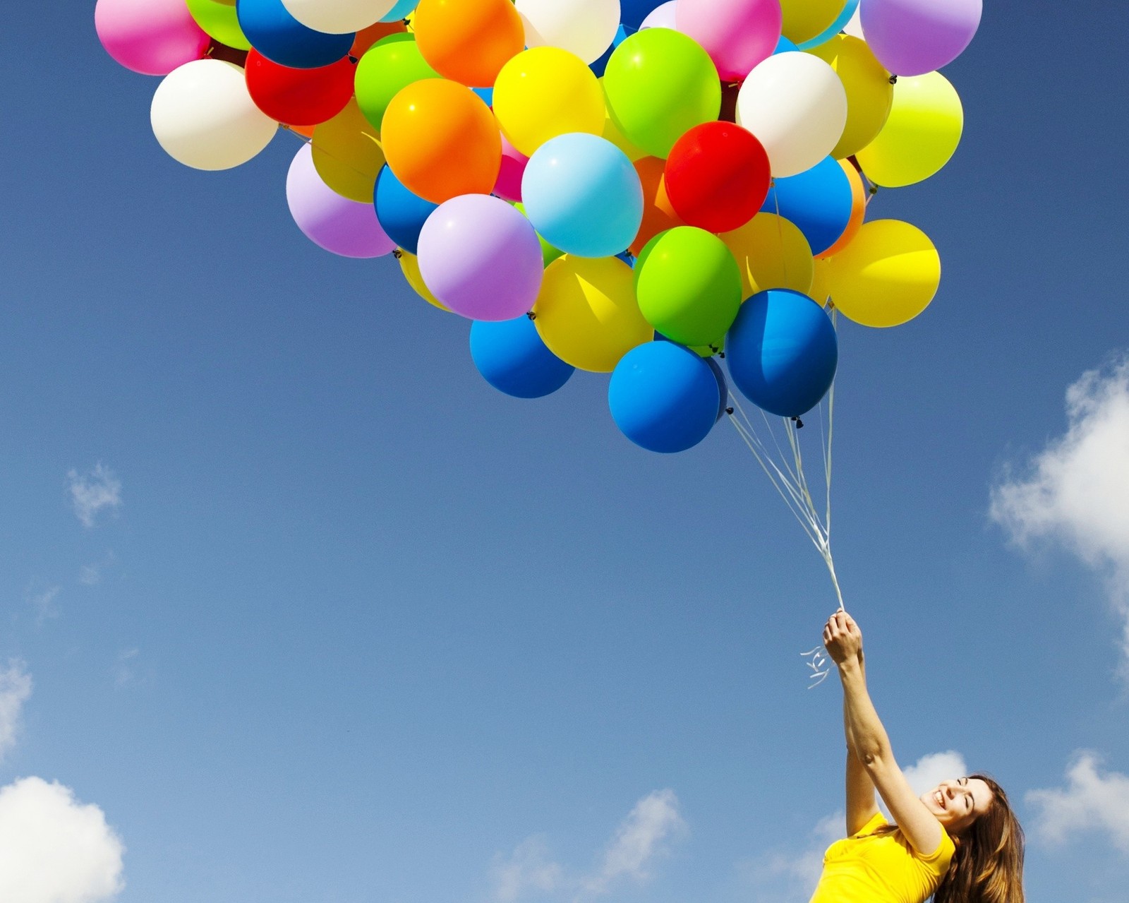 Une femme tient une poignée de ballons dans les airs (ballon, coloré, heureux, ciel, femme)