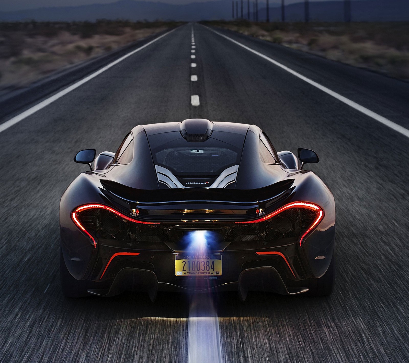 Un gros plan d'une voiture de sport noire roulant sur une route (britannique, mclaren, mcclaren, p1, route)