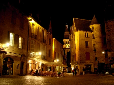 Charmante place médiévale illuminée la nuit, mettant en valeur une architecture historique et une restauration en plein air dans une capitale vibrante.