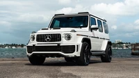 Elegante SUV Mercedes AMG G 63 branco contra um fundo urbano à beira-mar