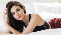 Victoria Justice in einer stilvollen Pose auf einem Bett, die ihre Eleganz und Schönheit zeigt.