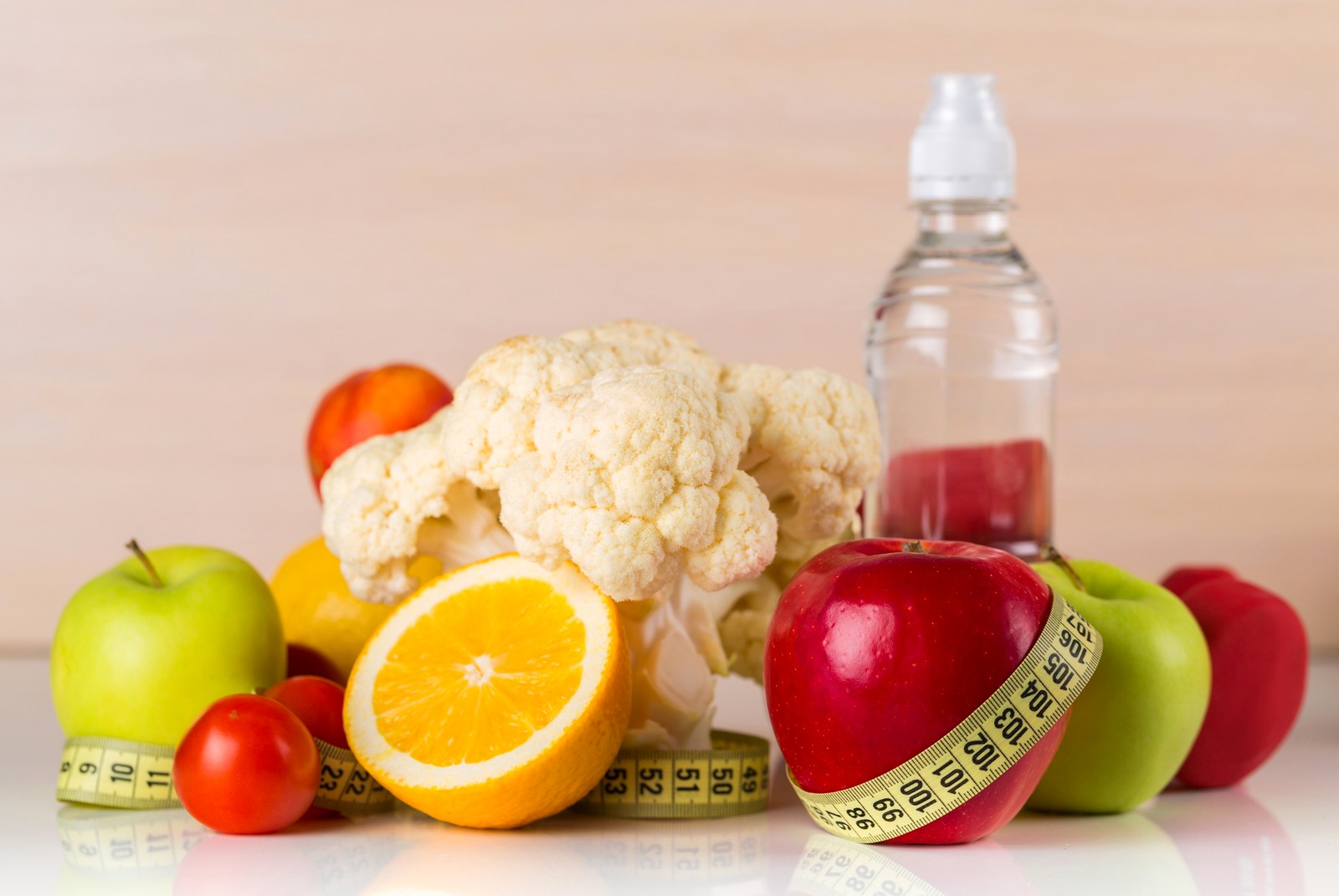 There is a bottle of water and a measuring tape next to some fruits (natural foods, fruit, vegetarian cuisine, vegetable, food)