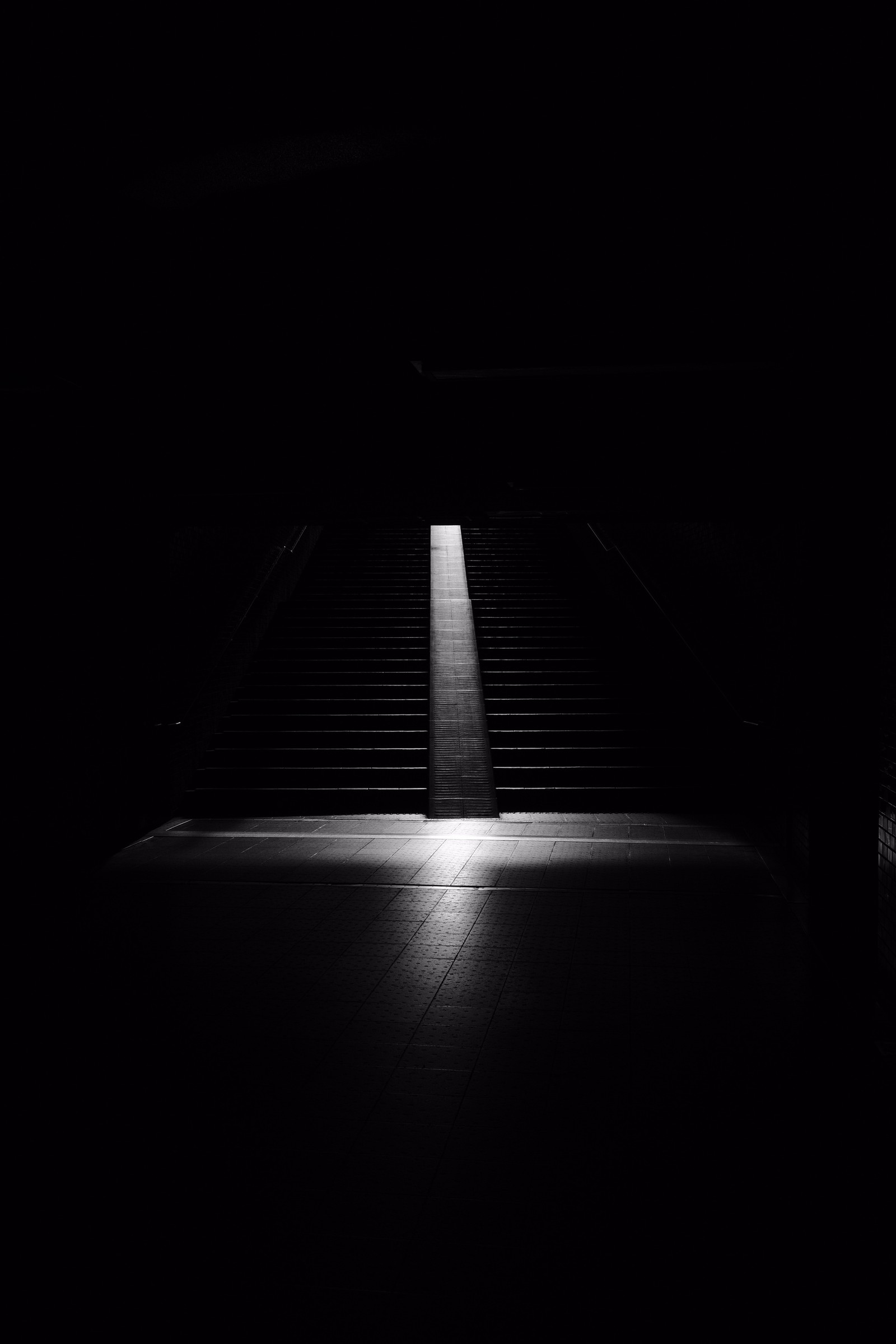 Una escalera débilmente iluminada que lleva a un conjunto de escaleras en una habitación oscura (cielo, blanco y negro, mural, negro, pasos)