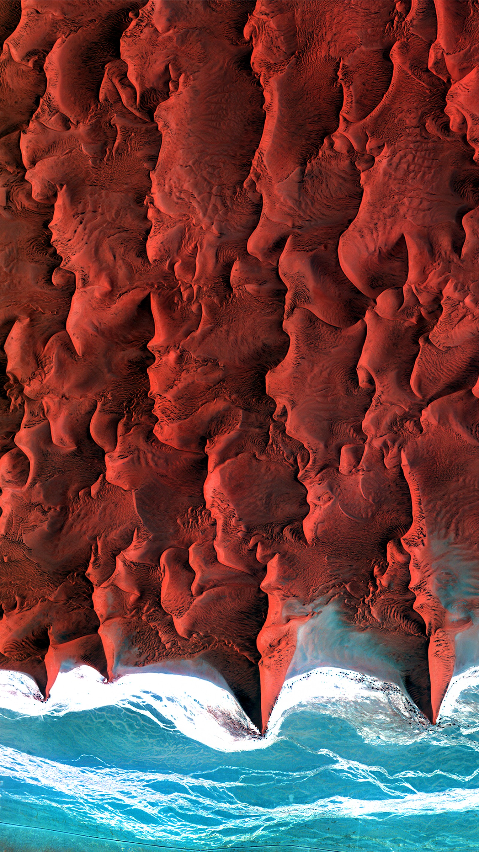 Arafed view of a red sand dune with a wave coming in (desert, namibia, earth, red, liquid)