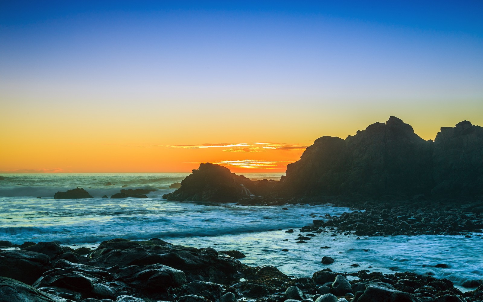 Vue arabe d'une plage rocheuse avec un coucher de soleil en arrière-plan (mer, océan, nature, horizon, la côte)