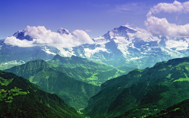 Горы со снежными вершинами и зелеными долинами на горизонте (jungfrau peak, eiger, monch, бернские альпы, швейцария)