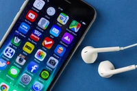 Smartphone da Apple com fones de ouvido em fundo azul