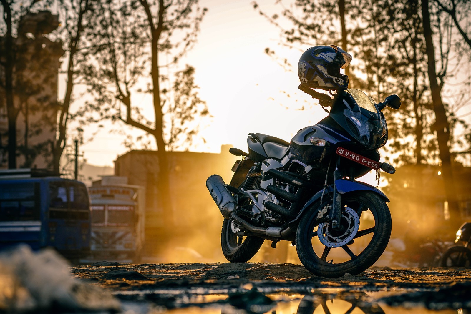 Una motocicleta estacionada en un terreno fangoso con un casco encima (casco de motocicleta, motocicleta, seguridad de motocicletas, deporte extremo, motociclismo)