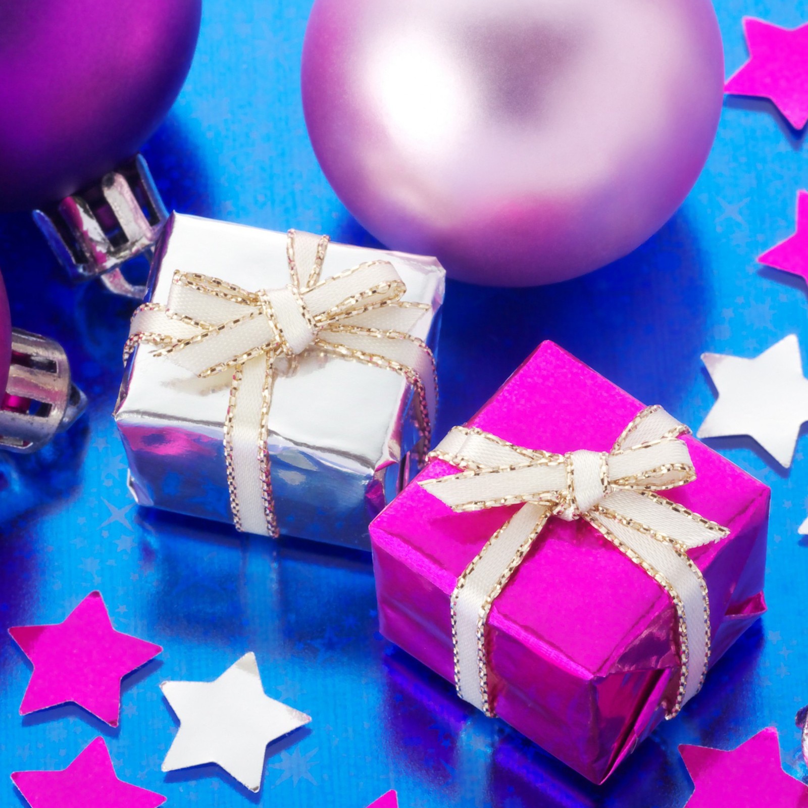 Decoraciones navideñas moradas y blancas y una caja de regalo rosa sobre una superficie azul (regalos de navidad, regalos, festivo)