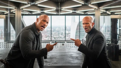 Dwayne Johnson and Jason Statham in a tense standoff in "Hobbs & Shaw" with a city skyline backdrop.