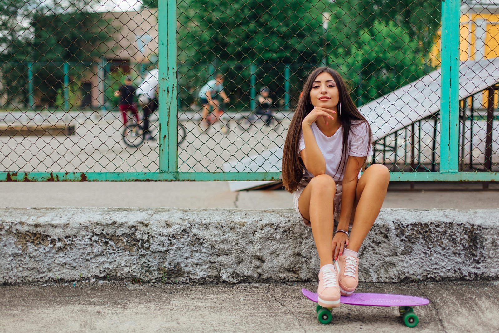 Araffe assis sur un skateboard sur le trottoir devant une clôture (vert, beauté, chaussures, mode de rue, lèvre)