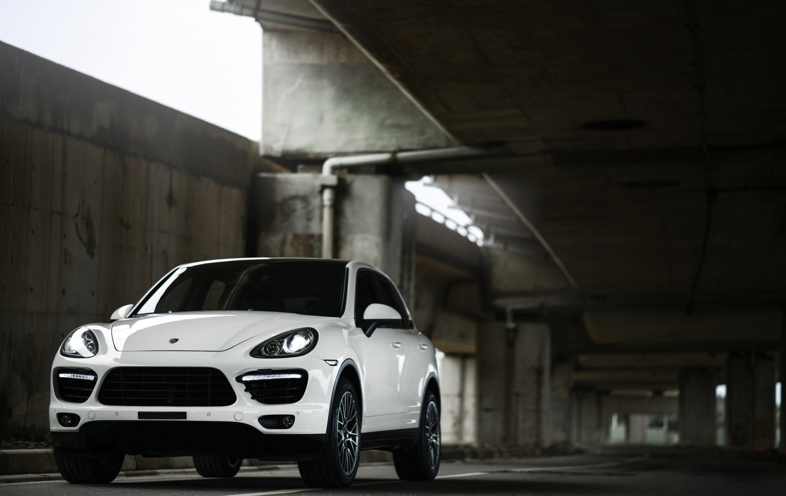 Arafed view of a white porsche cayen parked in a parking garage (porsche cayenne, porsche, car, rim, city car)