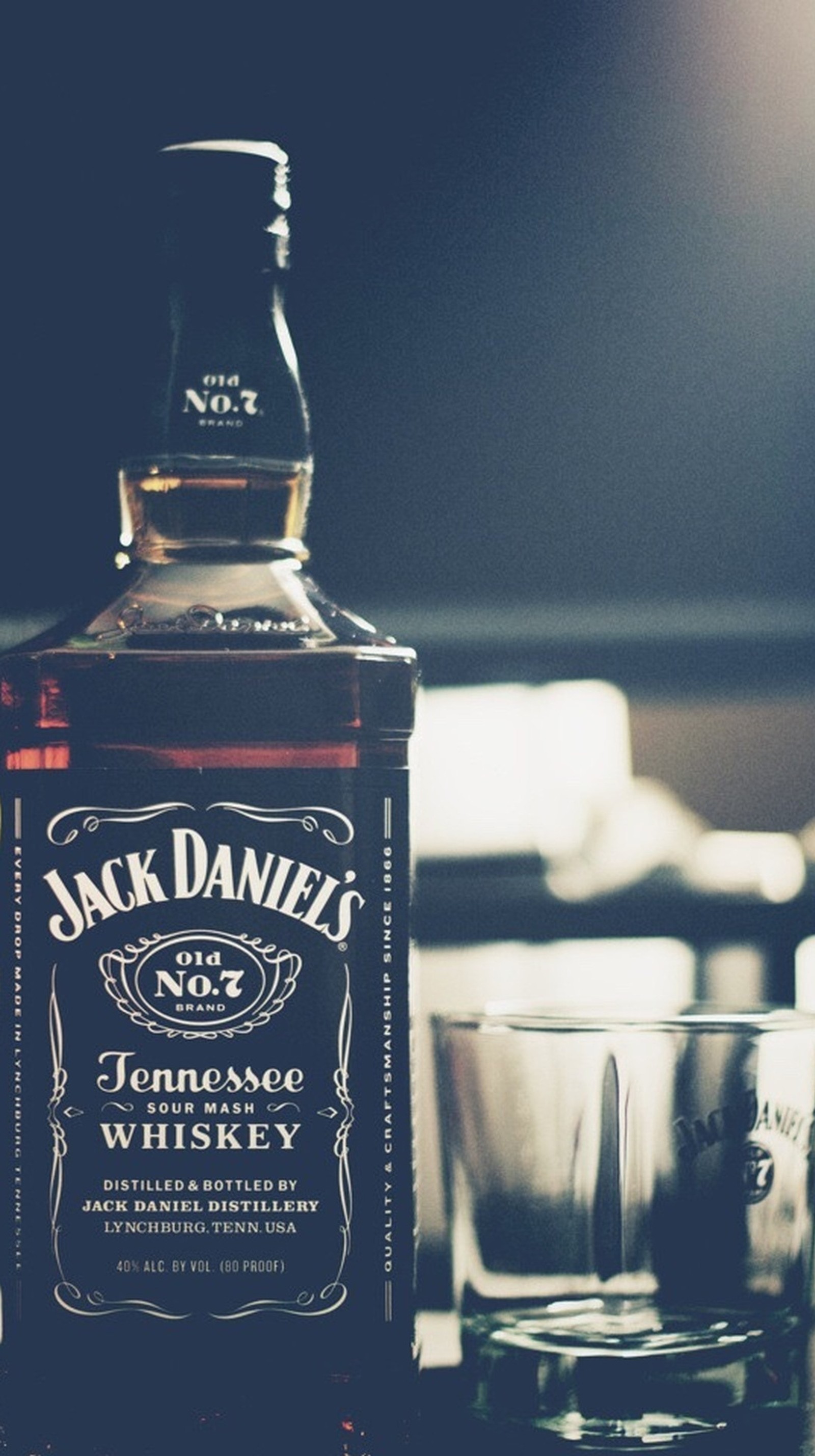 Una botella de whisky jack daniels al lado de un vaso (daniels, jack)