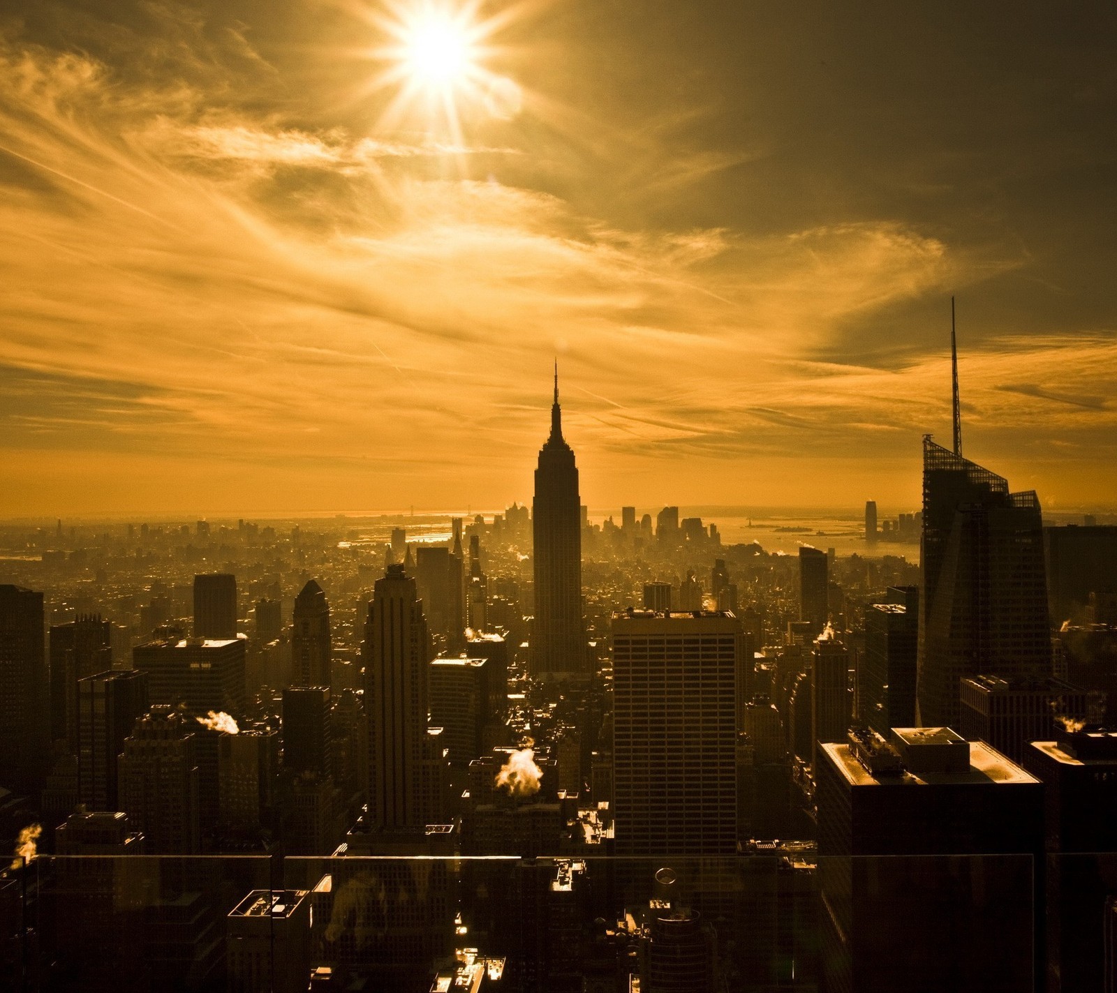 Vista ferida de uma cidade com o sol brilhando sobre os prédios (empire state, manhattan, nova york, new york, nyc)