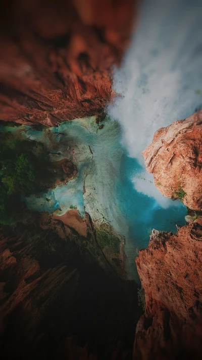 Vue aérienne d'un lac vibrant entouré de falaises rocheuses et d'une végétation luxuriante.