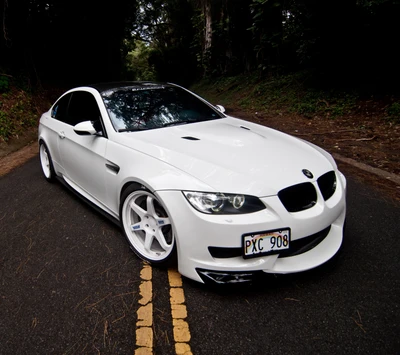 Eleganter weißer BMW M3 mit maßgeschneiderten Rädern auf einer malerischen Straße.