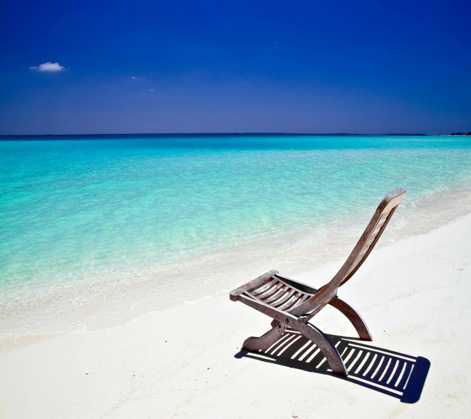 Une chaise arafed sur la plage avec un ciel bleu et de l'eau en arrière-plan (plage, détente)