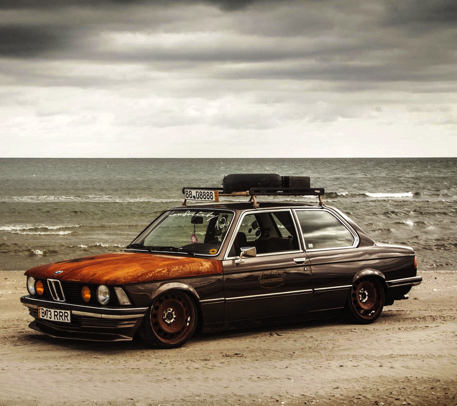 Hay un coche estacionado en la playa cerca del agua (bmw, coche, alemán, rata)