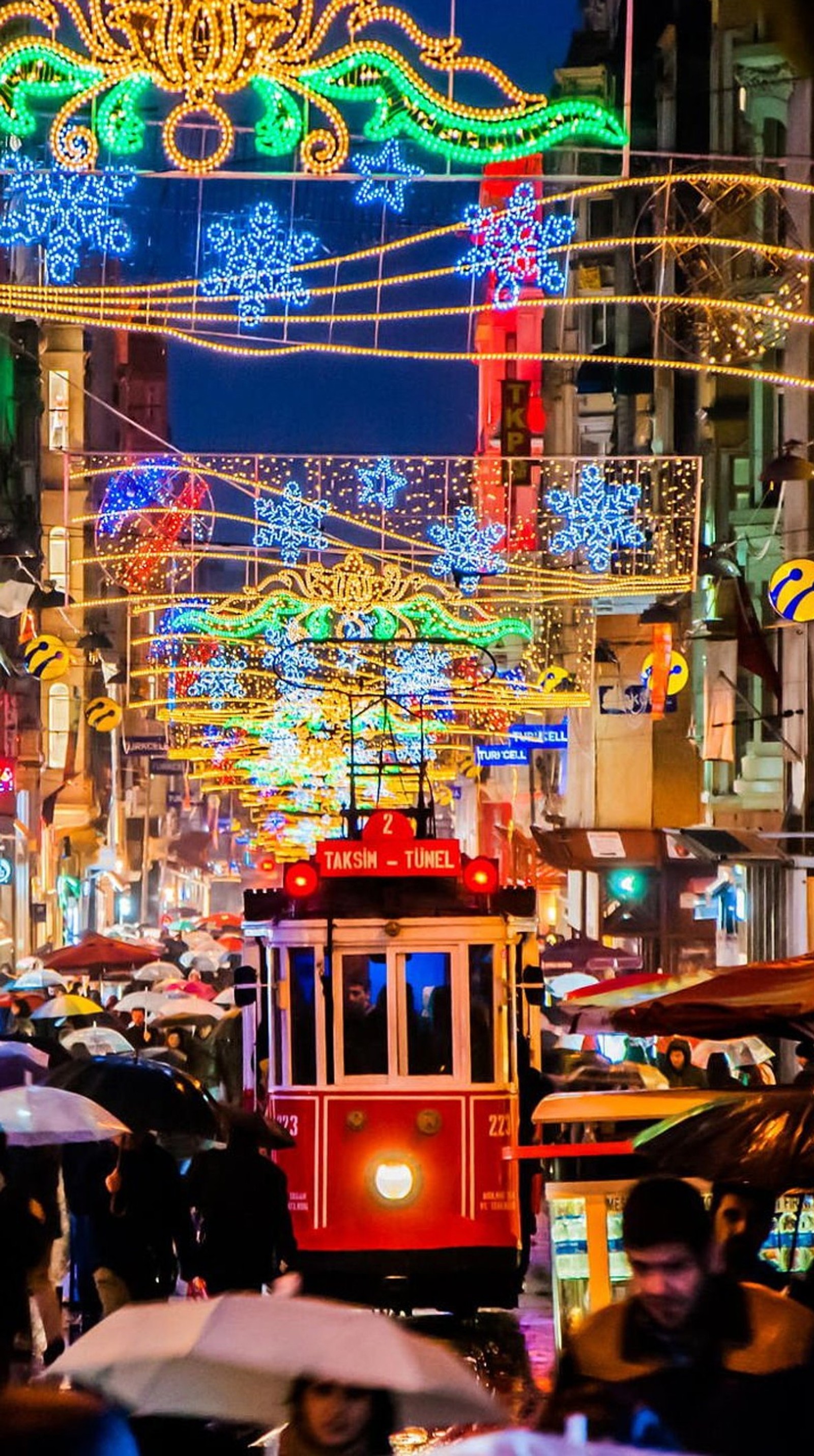 Um carrinho em uma rua da cidade com luzes de natal e pessoas (cidade, luzes, noite, peru)