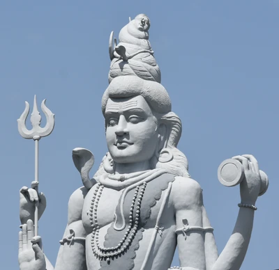 Statue majestueuse du Seigneur Shiva, ornée d'attributs traditionnels et se dressant contre un ciel bleu clair, symbolisant la spiritualité à Chittoor, Inde.