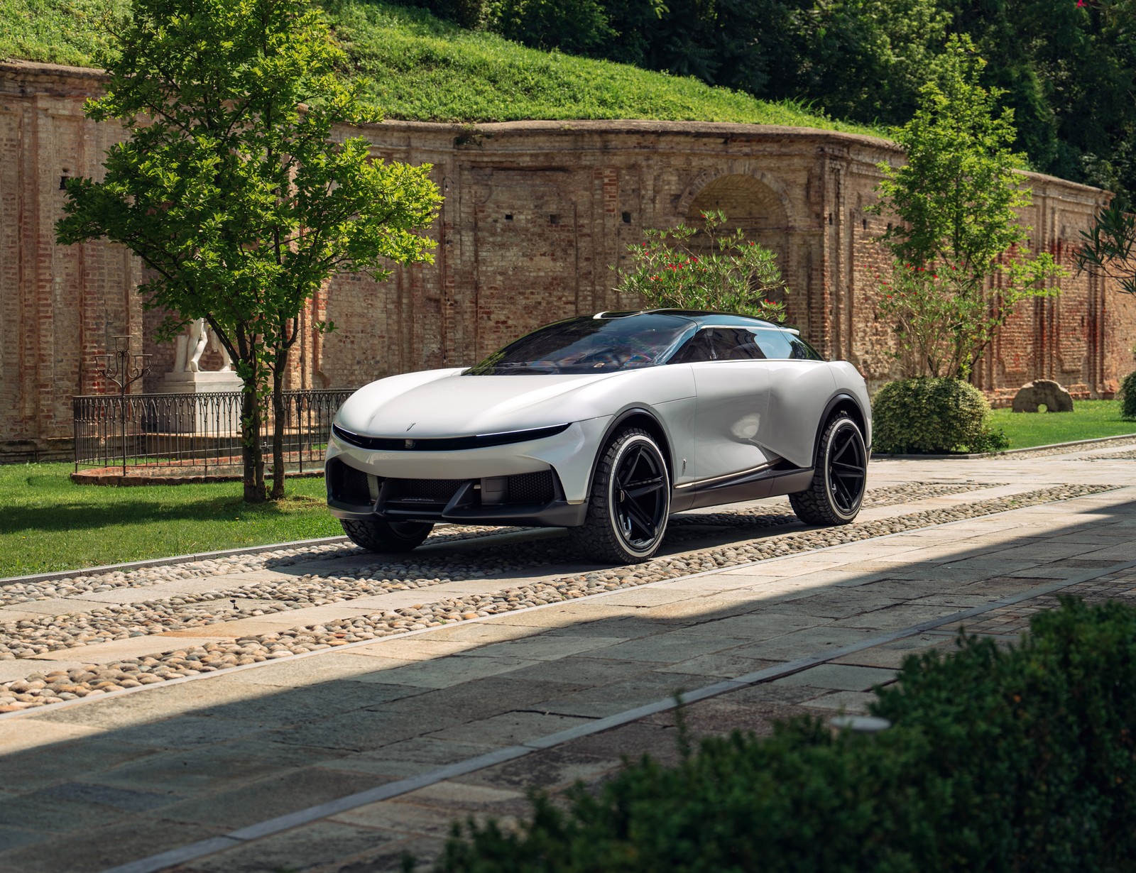 Un coche blanco conduciendo por una carretera al lado de un edificio de ladrillo (pininfarina pura vision, coches conceptuales, coches eléctricos de lujo, 5k, coches)