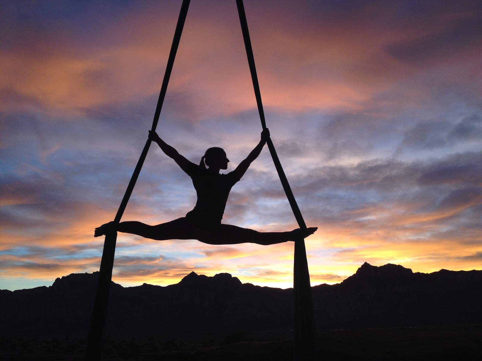 Eine skaterfrau, die im gebirge bei sonnenuntergang luftyoga macht (physische fitness, yoga, gleichgewicht, wolke, sonnenuntergang)