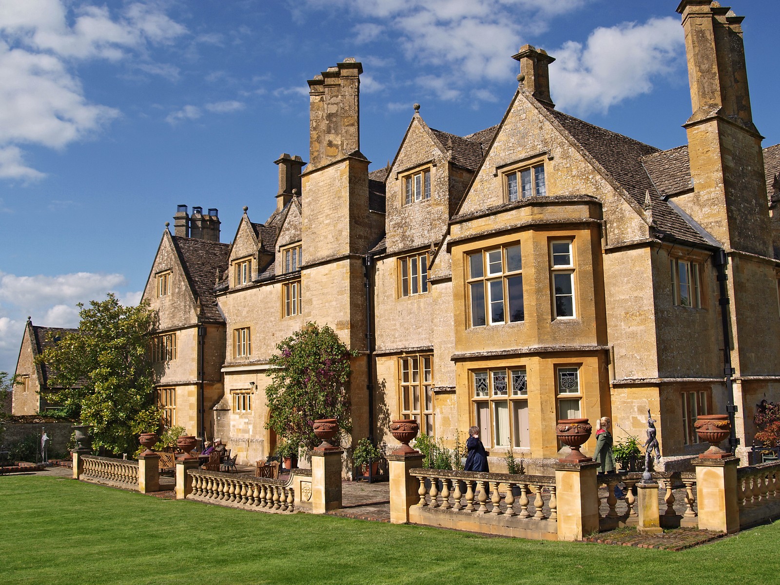 Arafed building with a lawn and a fence in front of it (stately home, building, medieval architecture, cottage, property)