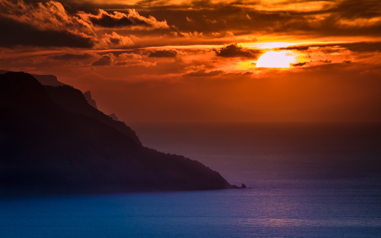 Vista de un atardecer sobre el océano con un barco en el agua (isla de mallorca, españa, naranja atardecer, cielo nublado, océano)