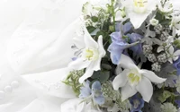 Elegante ramo floral blanco y azul con lirios y delicada vegetación, perfecto para una boda.