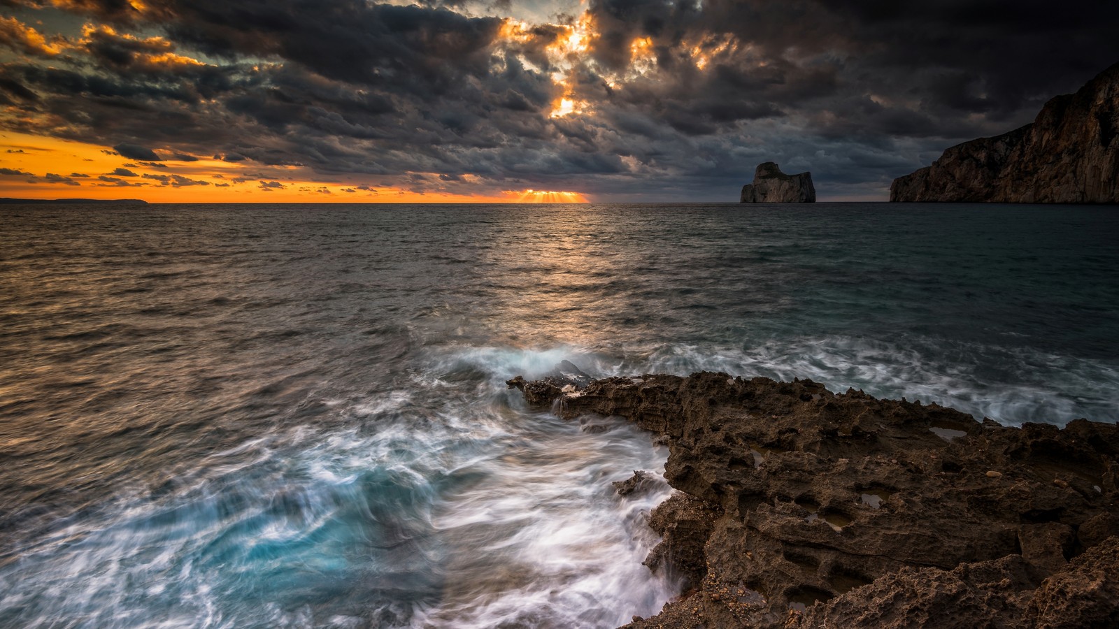 Un coucher de soleil sur l'océan avec des rochers et des vagues (mer, nuage, eau, ressources en eau, paysage naturel)