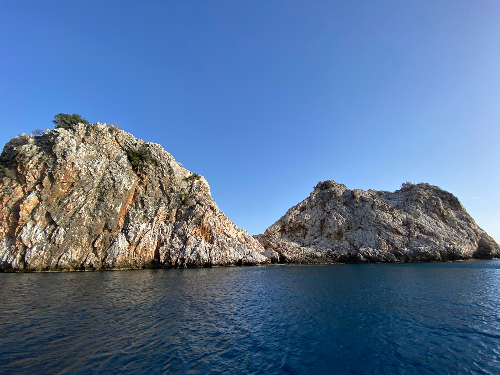 A view of a rocky island with a few small rocks in the water (sea, water, water resources, mountain, natural landscape)