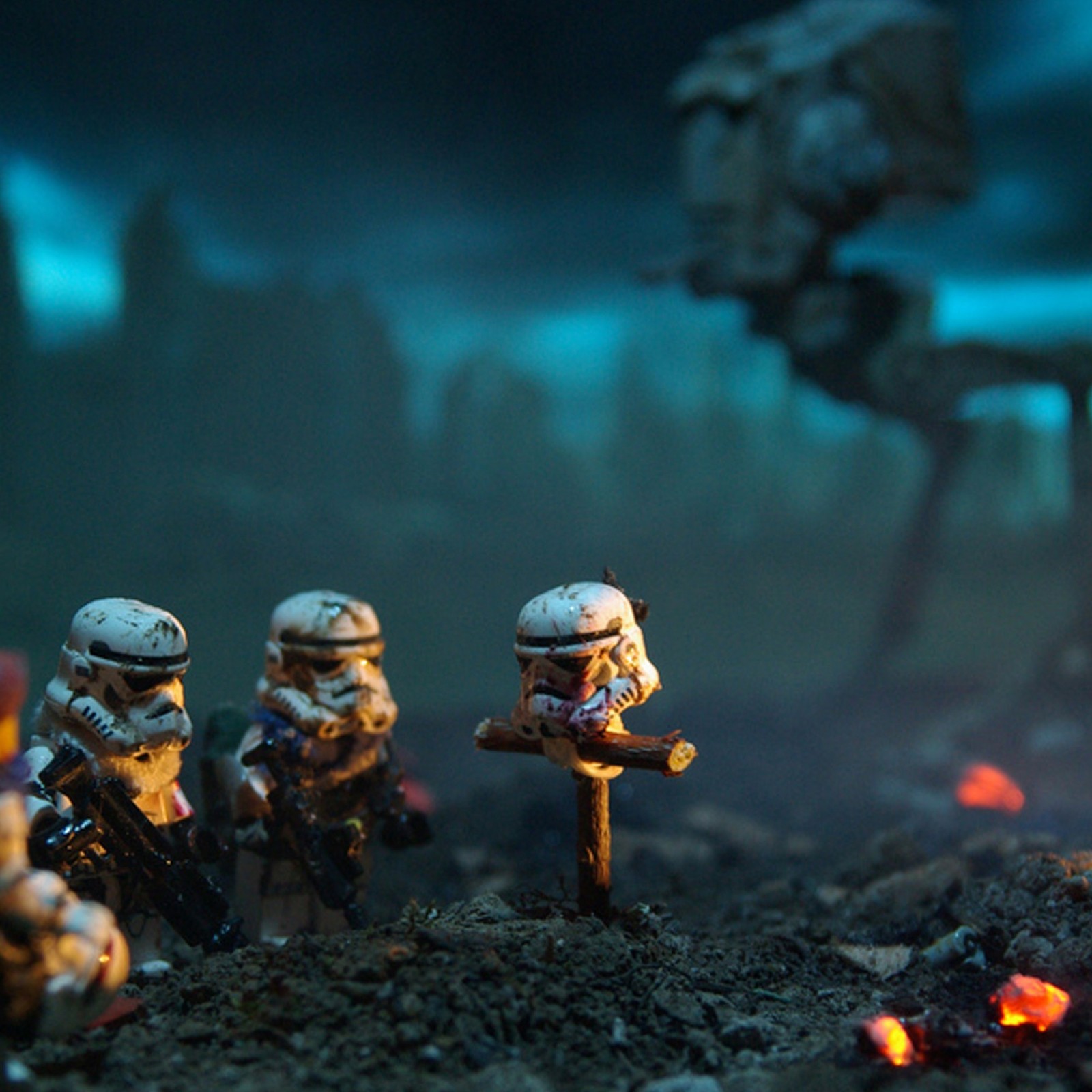 There are many toy soldiers that are standing in the dirt (legos, starwars, strom troopers)