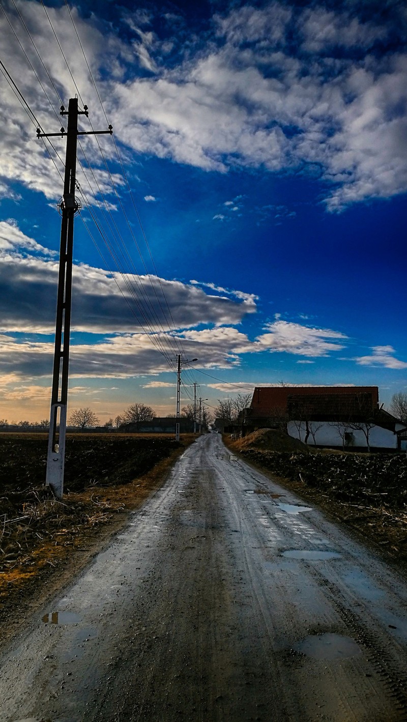 Пустая dirt road с телефонным столбом (красота, серебро)